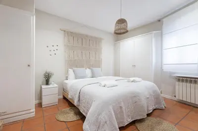 a white bedroom with a large bed with towels on it at La Casita - centro histórico y playa in Sitges