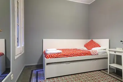 a small bedroom with a bed with red and white pillows at Apartments Barcelona & Home Deco Eixample in Barcelona
