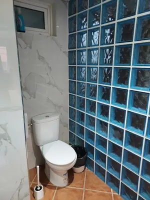 a bathroom with a toilet and blue tiled walls at Barcelona Village Homestay in Tiana