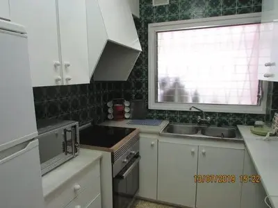 a kitchen with white cabinets and a sink and a window at Apart.con piscina en Sitges zona residencial in Sitges