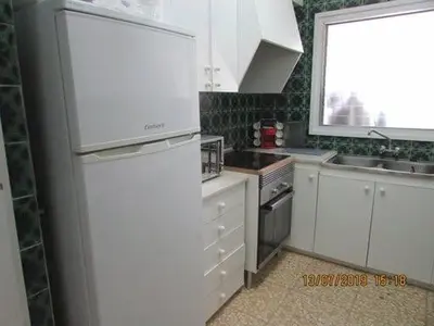 a kitchen with a white refrigerator and a window at Apart.con piscina en Sitges zona residencial in Sitges