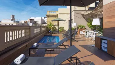 a balcony with a pool and chairs and an umbrella at H10 Urquinaona Plaza in Barcelona