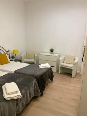 a bedroom with two beds and two chairs at 555 Apartments BCN in Barcelona
