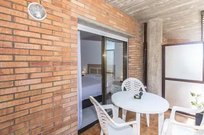 a brick walled room with a white table and chairs at HomeHolidaysRentals Frida in Pineda de Mar