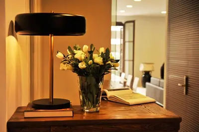 a vase of flowers on a table with a lamp and a book at The 8 Boutique B&B in Barcelona