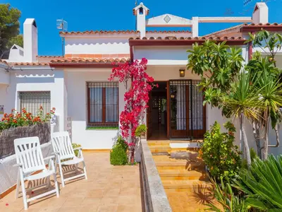 a house with two chairs and flowers in front of it at Holiday Home Remedios by Interhome in Cunit