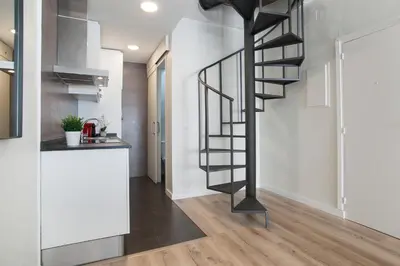 a spiral staircase in a living room with a kitchen at Tendency Apartments 8 in Barcelona