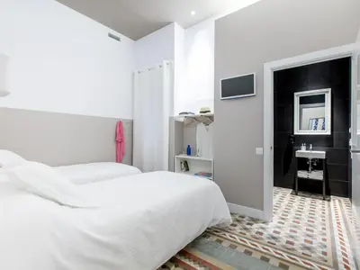 a white bedroom with a bed and a tv at Ecozentric in Barcelona