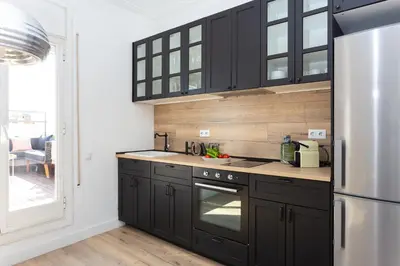 a kitchen with black cabinets and a stainless steel refrigerator at Casa Cosi - Atico in Barcelona