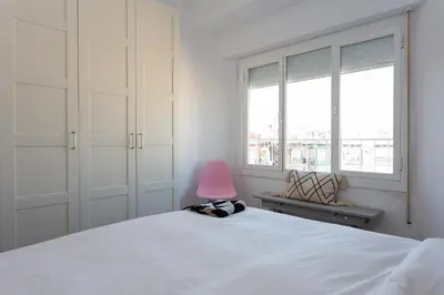 a bedroom with a white bed and a pink chair at Casa Cosi - Atico in Barcelona