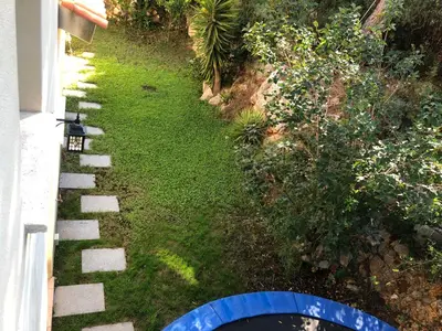 a garden with grass and a blue object next to a house at Casa Bella Vista en montaña con vistas al mar y piscina privada in Cunit
