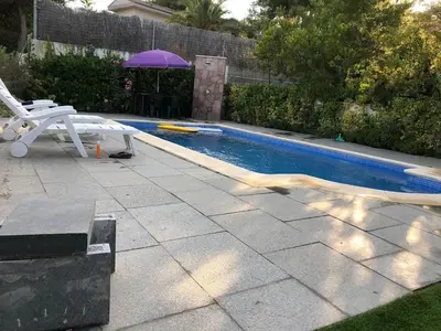 a swimming pool with a bench and an umbrella at Casa Bella Vista en montaña con vistas al mar y piscina privada in Cunit