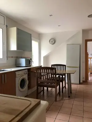 a kitchen with a table and chairs and a refrigerator at Casa Bella Vista en montaña con vistas al mar y piscina privada in Cunit