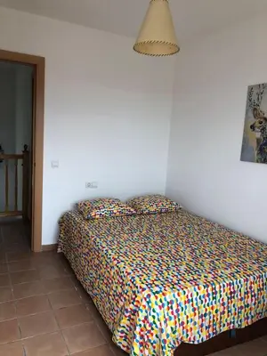 a bedroom with a bed with a colorful comforter at Casa Bella Vista en montaña con vistas al mar y piscina privada in Cunit
