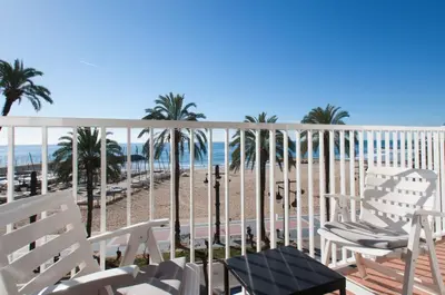 a balcony with white chairs and a view of the beach at Sunny Apartments in Sitges