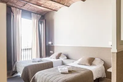 two beds in a room with a window at Apartments HHB in Barcelona