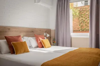 a bedroom with a white bed with colorful pillows at BYPILLOW House in Barcelona