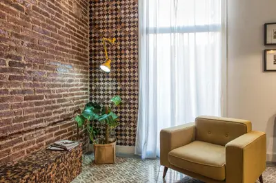 a living room with a chair and a brick wall at Brummell Apartments Eixample Izquierda/Valeris in Barcelona