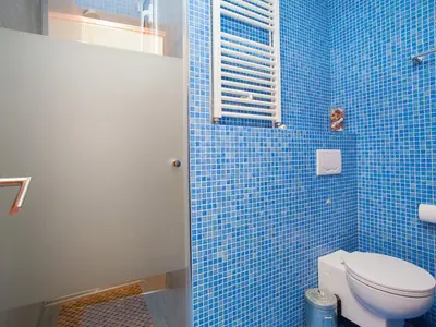 a blue tiled bathroom with a toilet and a window at Apartment Sardenya - Casp by Interhome in Barcelona