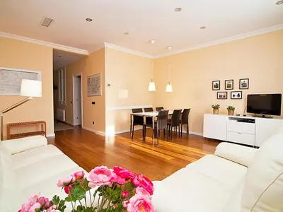a living room with white furniture and a table with pink flowers at Apartment Eixample Esquerre Gran Via Balmes by Interhome in Barcelona