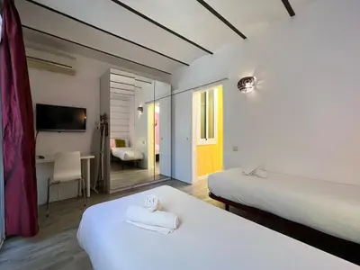 a hotel room with two beds and a desk at Stay U-nique Apartments Fontrodona in Barcelona