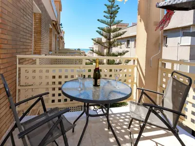 a table with a bottle of wine and two chairs on a balcony at Apartment Aires de mar by Interhome in Cunit