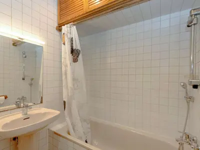 a white tiled bathroom with a sink and a tub at Apartment Eixample Esquerre Arago Rocafort by Interhome in Barcelona