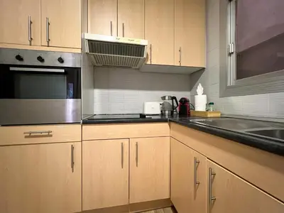 a kitchen with wooden cabinets and a sink and a microwave at Stay U-nique Apartments Sardenya II in Barcelona
