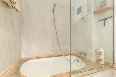 a bathroom with a glass shower with a tub at Alos Apartments Paseo de Gracia-Diagonal in Barcelona