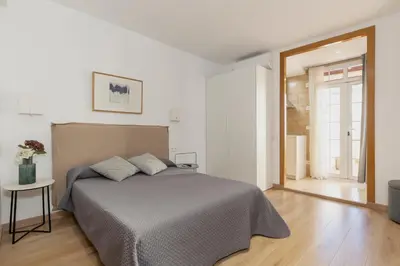 a white bedroom with a bed and a table at Alos Apartments Paseo de Gracia-Diagonal in Barcelona