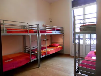 a room with three bunk beds and a window at Barcelona Central Garden Hostal in Barcelona