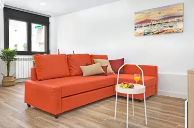 an orange couch in a living room with a table at Stay U-nique Apartments Fabra i Puig in Barcelona