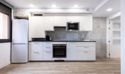a white kitchen with white cabinets and appliances at Stay U-nique Apartments Fabra i Puig in Barcelona