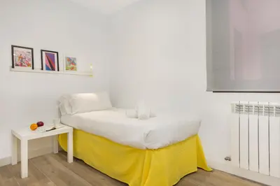 a bed with a yellow blanket and a table in a room at Stay U-nique Apartments Fabra i Puig in Barcelona