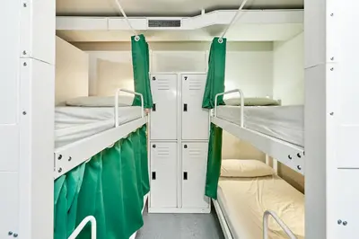 a room with two bunk beds and green curtains at Hola Hostal Eixample in Barcelona