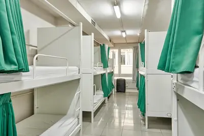 a room with white bunk beds and green curtains at Hola Hostal Eixample in Barcelona