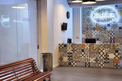 a bench sitting in front of a counter with tiles at Hola Hostal Eixample in Barcelona