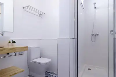 a white bathroom with a toilet and a shower at Ola Living Camp Nou in Hospitalet de Llobregat