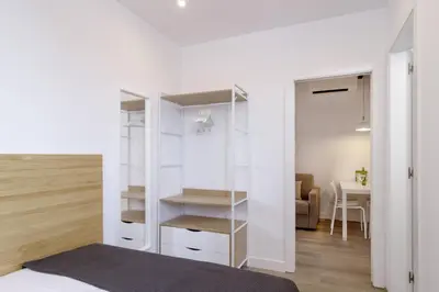 a bedroom with a white closet and a table at Ola Living Camp Nou in Hospitalet de Llobregat