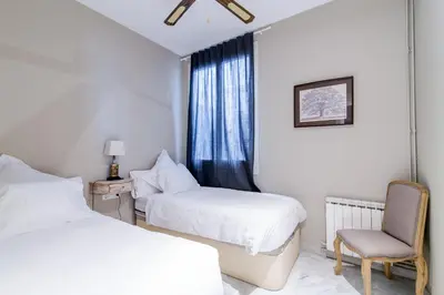 a bedroom with two beds and a chair and a window at BCN Apartments 41 in Barcelona