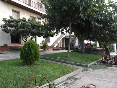 a yard of a building with a house and a wheel in the grass at Mas Cabrit in Les Franqueses del Vallès