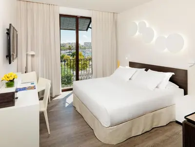 a hotel room with a bed and a desk and a window at H10 Port Vell 4* Sup in Barcelona