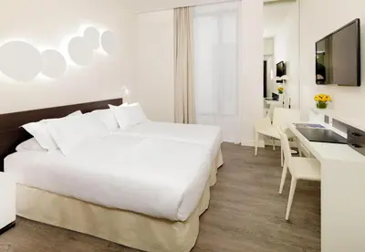 a hotel room with a white bed and a desk at H10 Port Vell 4* Sup in Barcelona