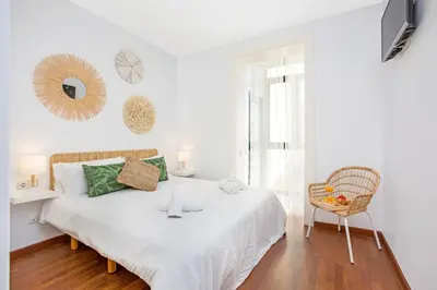 a white bedroom with a bed and a chair at Stay U-nique Apartments Girona in Barcelona