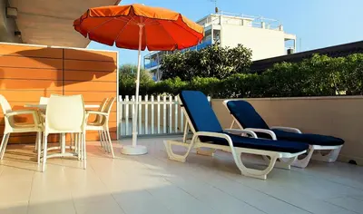 a patio with a table and chairs and an umbrella at Apartaments Maritim in Castelldefels