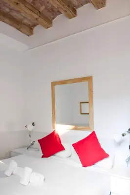 a bedroom with a white bed with red pillows at My Address in Barcelona Old Town in Barcelona