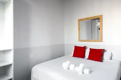 a white bed with red pillows and a mirror at My Address in Barcelona Old Town in Barcelona