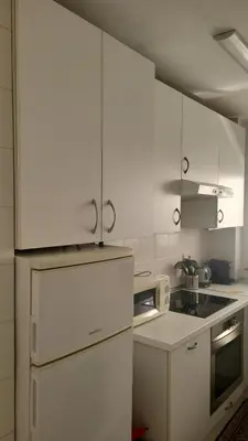 a kitchen with white cabinets and a white refrigerator at ESPIGALL in Vilanova i la Geltrú