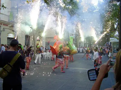 a group of people dancing in a parade on a street at ESPIGALL in Vilanova i la Geltrú
