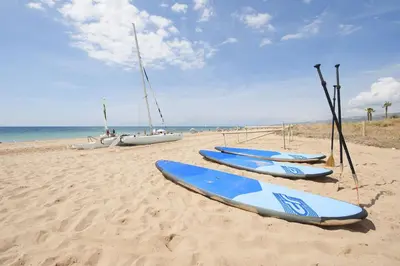 a row of surfboards on a beach with boats at White Sea by Seasidehomes in Castelldefels